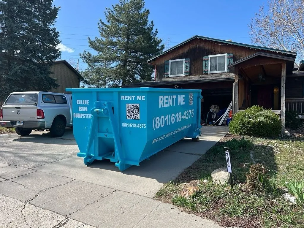 A Blue Bin dumpster set down in a residential driveway